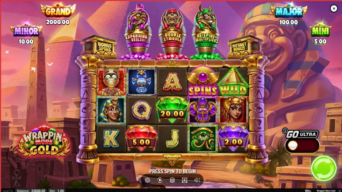 Tampilan visual slot Wrappin’ More Gold dengan mumi ramah dan latar belakang Mesir Kuno